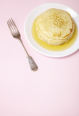 A stack of hotcakes with golden syrup on a pastel pink background forming a page header