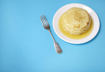 A stack of pancakes with golden syrup on a bright blue background forming a page border