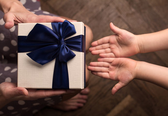 Mother giving a big gift boxes to her kid with open hand