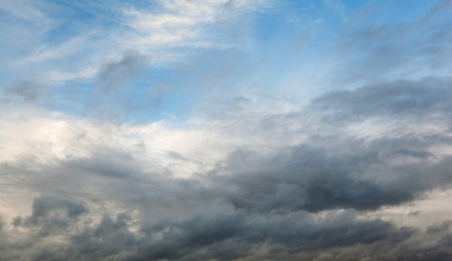 Beautiful dramatic sky with gray clouds and sunset. Dark blue feather shaped clouds in the background of bright orange sunset.