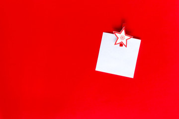 Christmas clothespegs with a white note paper on a red backgroun