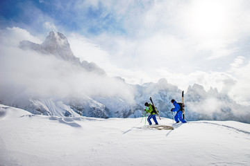 Two Skiers walking in the Dolomites with skies on their back, South Tyrol, Italy