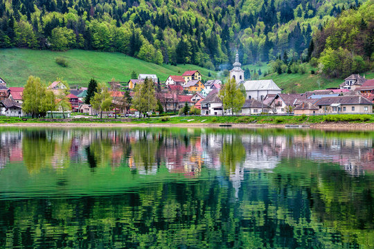 Village and forest reflected in lake