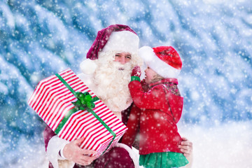 Santa Claus talking to little girl in snowy park