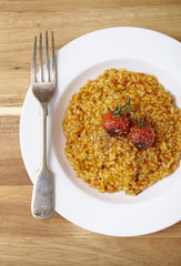 A dinner bowl of tomato risotto on a wooden table background