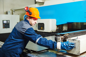 industrial factory worker operates punching machine - Powered by Adobe