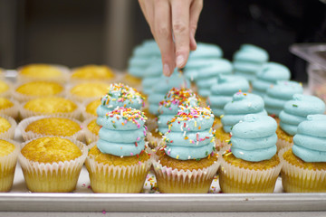 Baker Decorating Vanilla Cupcakes with Blue Frosting