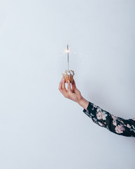Hand of woman holding cupcake with sparkler