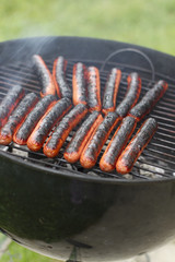 hot dogs on a simple black charcoal grill