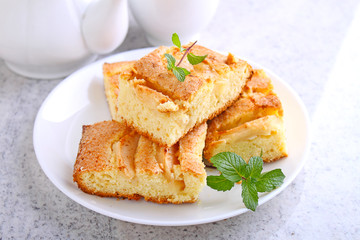 homemade pie with apples and cinnamon is cut slices on a plate, wooden background