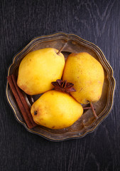 yellow pears in a metal plate on a black background