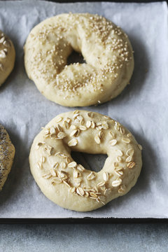 Bagels dough sprinkled with different types of seeds on tray