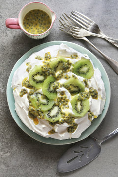 Pavlova with kiwi and passion fruit on a plate with a jug of pas