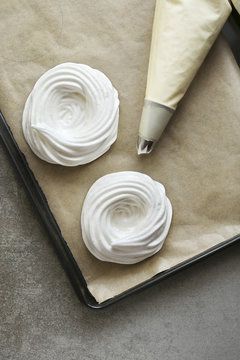 Meringue nests before baking on a tray lined with parchment pape