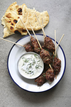 Turkish Kofta on an enamel plate with dill yogurt dressing