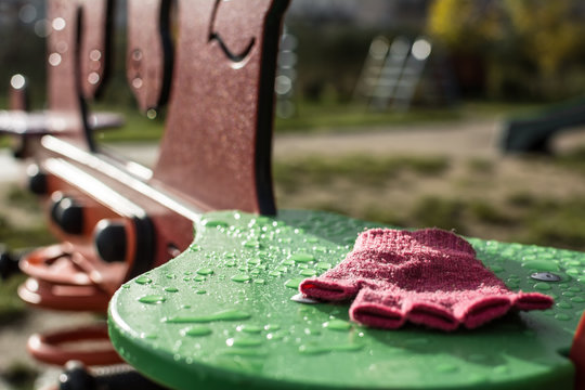 Pink child's glove abandoned on seesaw seat - creepy playground scenery, kidnapping metaphor. 