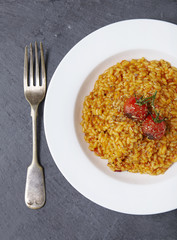 Aerial view of a dinner dish of tomato risotto on a rustic slate background