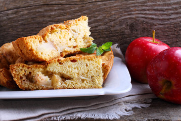 Charlotte with apples in the white plate on a wooden background