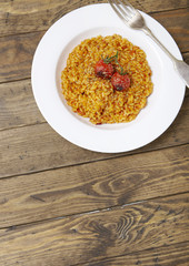 A dish of tomato risotto on a rustic wooden dinner table background forming a page header