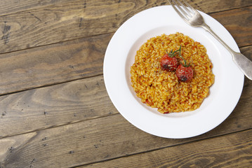 A dish of tomato risotto on a rustic wooden dinner table background forming a page border