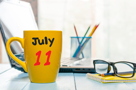 July 11th. Day 11 of month, color calendar on yellow morning coffee cup at business workplace background. Summer concept. Empty space for text