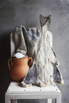 Salted cod fish and rustic pot with sea salt on white chair