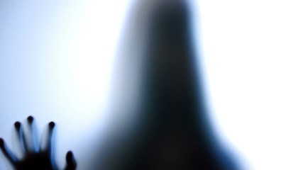 Psychotic woman pounding on glass, patient of mental hospital, creepy silhouette. Scary ghostly creature behind the glass

