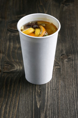 Drink with orange and lemon in a paper cup on the wooden table