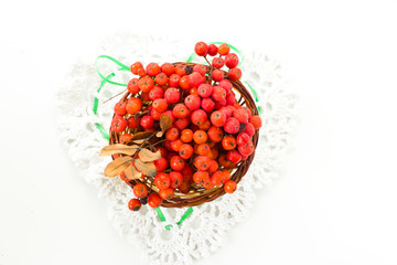 Branches of a mountain ash in the basket. White knitted heart.