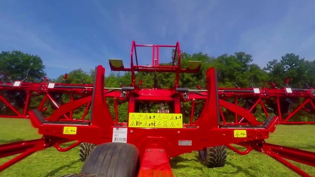 A man is pushing a button in a tractor and he folding rotary rakes on a machine. Close-up shot.
