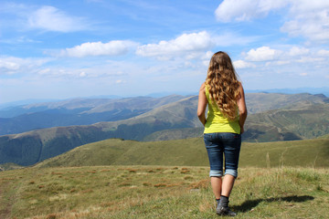 Naklejka premium The girl tourist with long hair looks at the mountains in clear