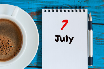 July 7th. Day 7 of month, calendar on business workplace background with morning coffee cup. Summer concept. Empty space for text