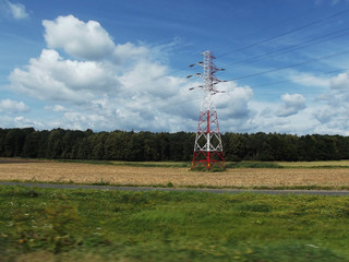 Krajobraz wiejski - pole, chmury, las i słup wysokiego napięcia