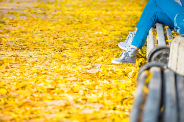 Fototapeta premium Young woman sitting on a bench in park