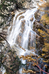 waterfall in the mountains and the autumnal trees, long exposure