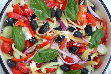 Greek salad with tomatoes, peppers, black olives, onion, basil and feta cheese. Top view, close-up. 