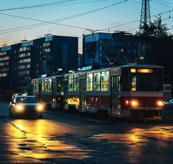 Obraz premium tram, car, dusk, city, people, headlights, dark house in the background