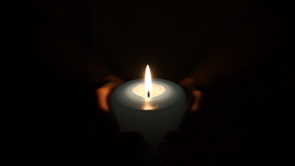 burning candle in the hands of women.