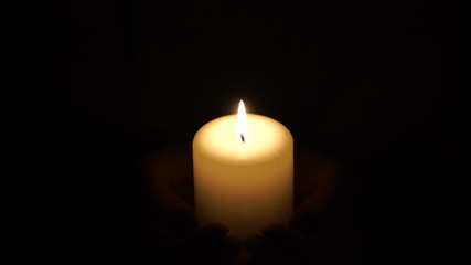 Fototapeta na wymiar burning candle in the hands of women.