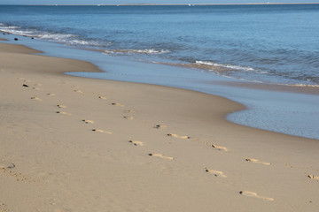 Beach, wave and footprints at sunset time