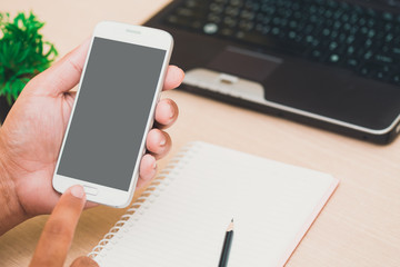 Businessman's hands holding and use mobile phone on on office table