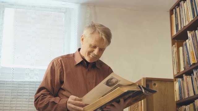 The old man looking through the book and smiling to the camera 4k