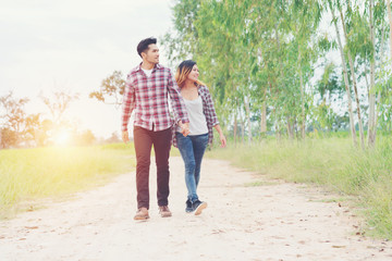 Obraz premium Young couple in love walking on rural road holding hands talking