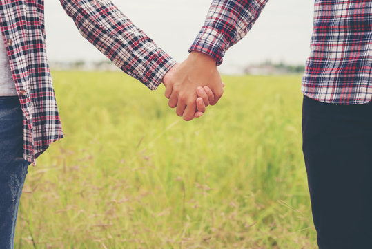 Close Up of loving couple holding hands while walking meadow fie