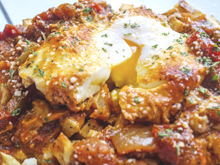 Eggs poached in tomato sauce over fried potatoes.
