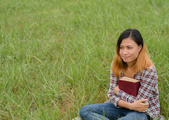 Young woman reading book on meadows field.