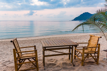 Table and chairs in the sunrise at a tanquil beach in Thailand