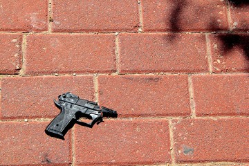 Broken Toy Gun on Red Brick