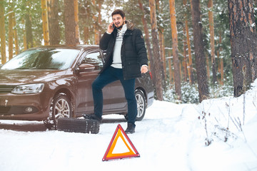 Upset young man calling the car service standing on the broken c