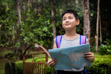 Naklejka premium Asian Chinese little boy holding map in the forest